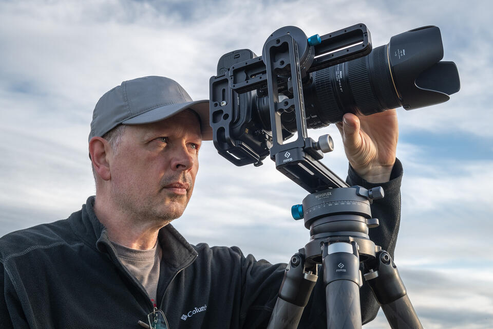 Closeup of photographer looking at back of camera mounted on tripod.
