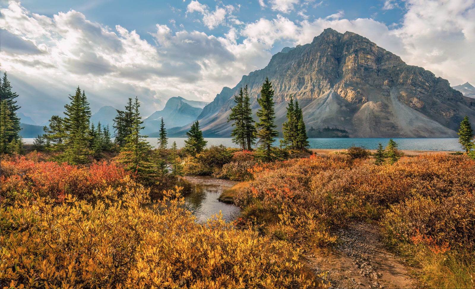 Bow Lake at sunrise with turquoise water, dramatic mountain peaks, and leading shoreline lines along the Icefields Parkway, Banff National Park.