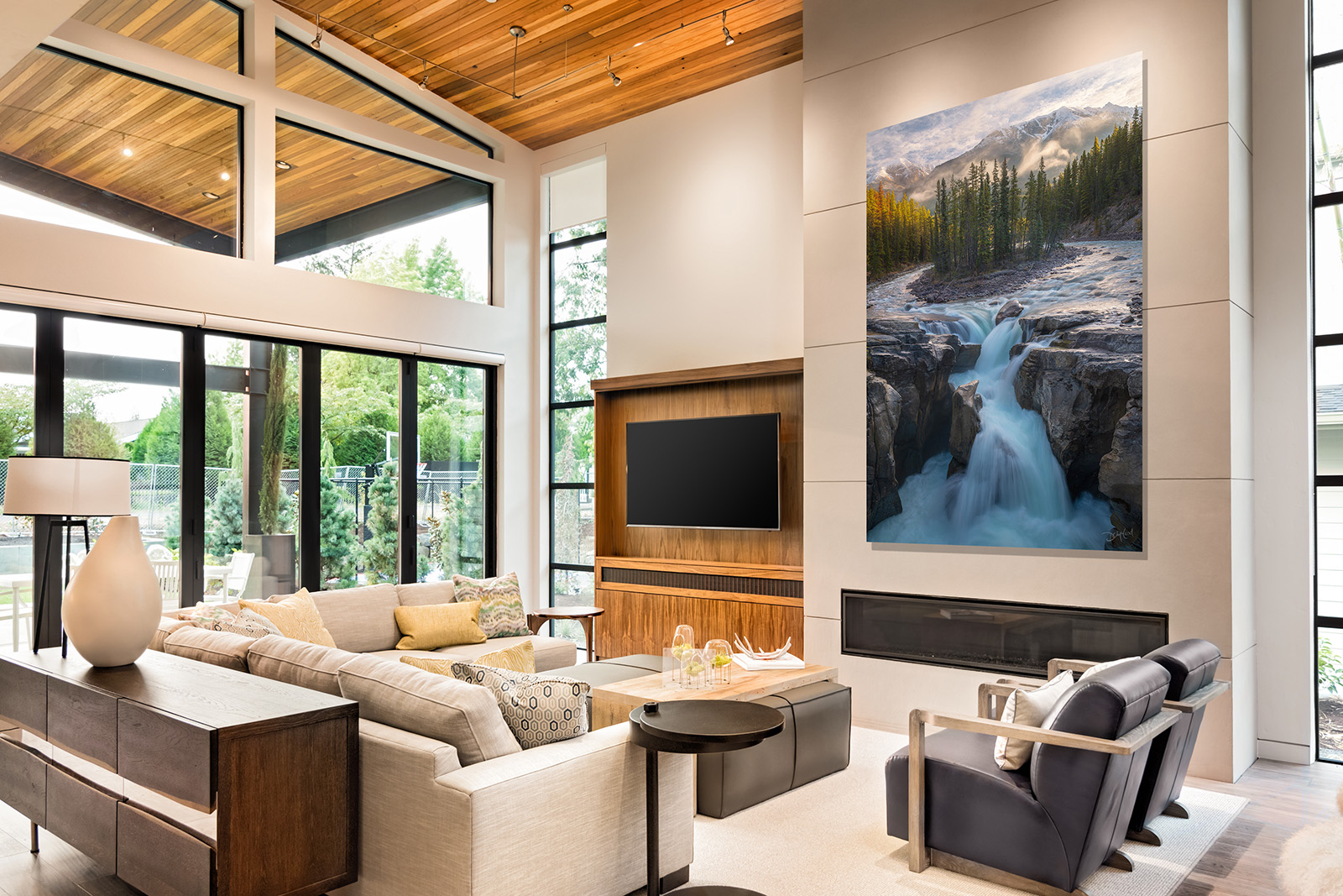 Modern chalet style great room with sofa, chairs, and photographic print of waterfall scene hanging above fireplace.