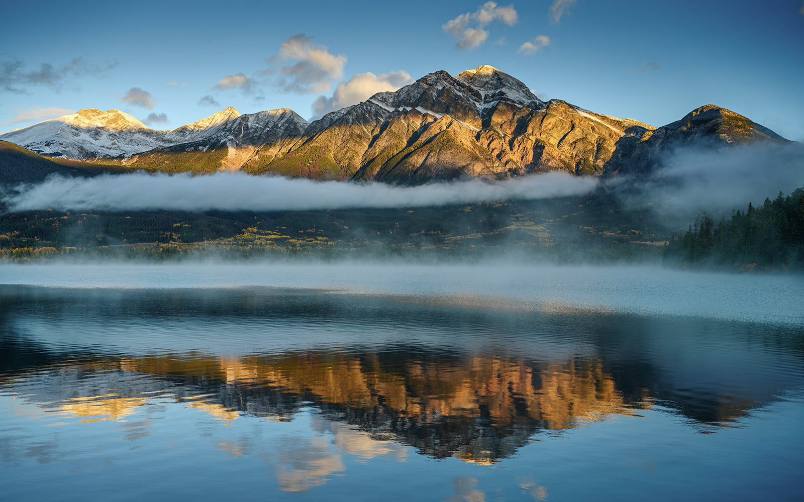 Pyramid Lake at sunrise with Pyramid Mountain reflected in calm water near Jasper, Alberta.