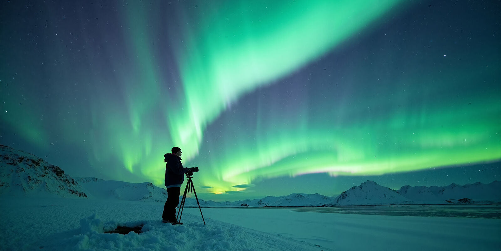 A photographer shoots the northern lights in winter in the mountains of Finland.