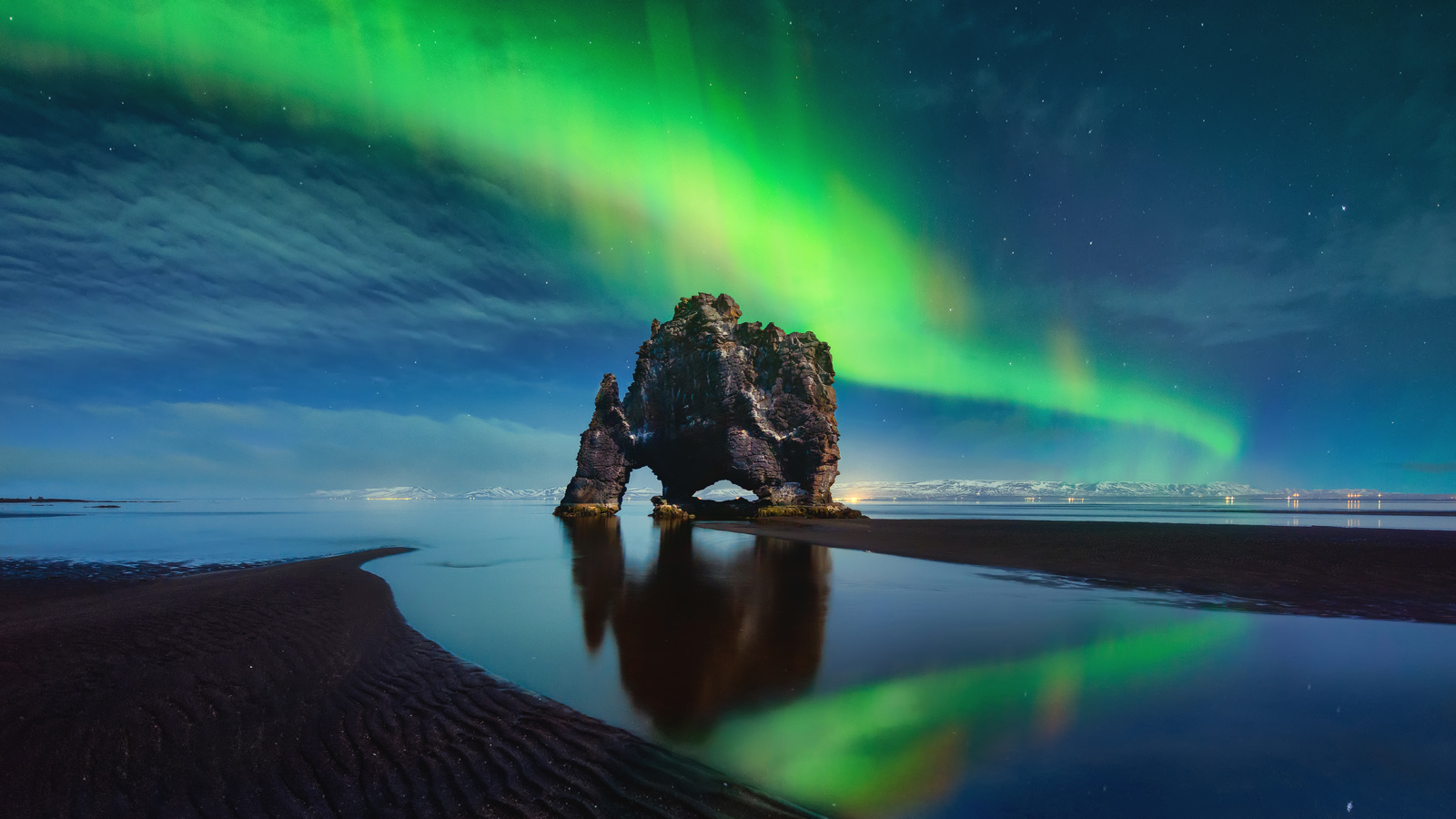 Hvitserkur in Iceland as the aurora in the sky reflects in the water.