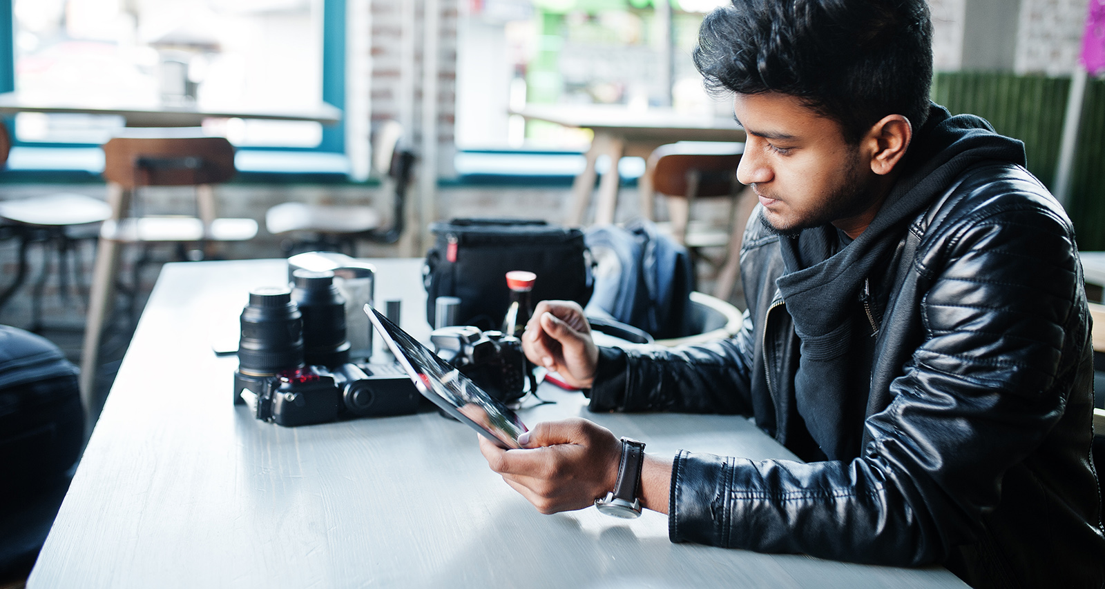 A photographer sits in a cafe checking his mobile tablet for aurora alerts.