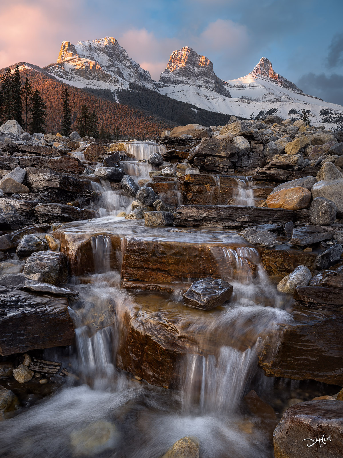 Three Sisters mountain peaks in Canmore with waterfall foreground at sunrise, fine art landscape photography print.